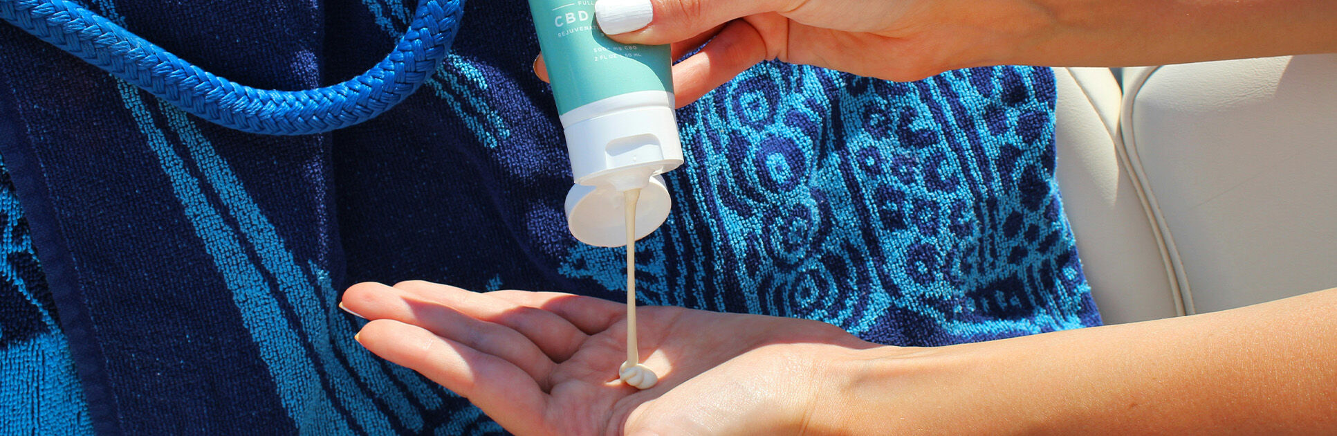 Aplicando creme na mão sobre toalha azul.