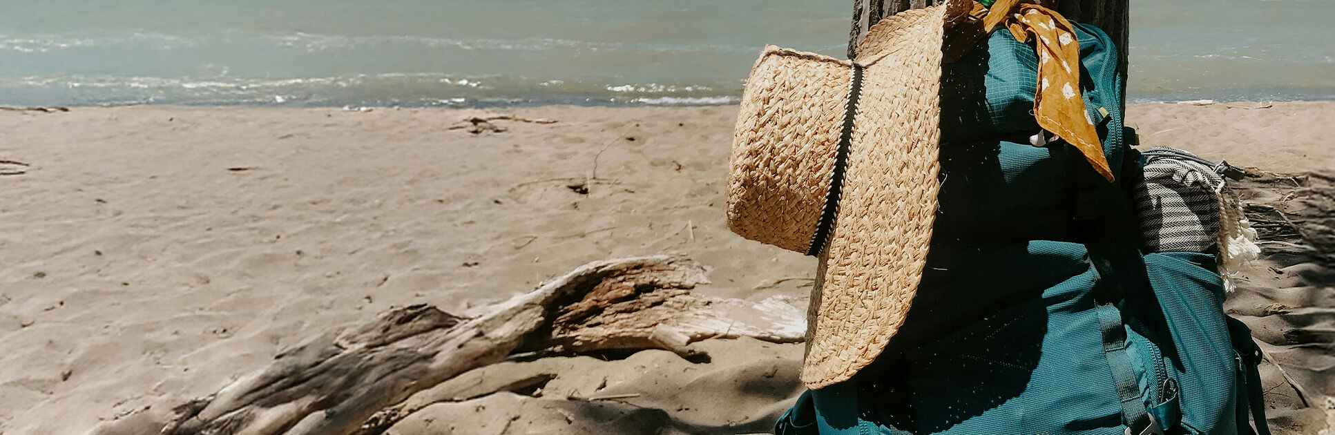 Mochila e chapéu em praia ensolarada