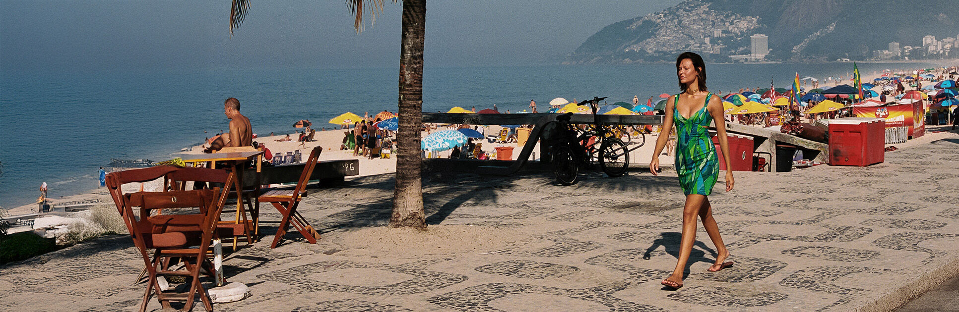 Mulher caminhando na praia com estrutura de quiosques