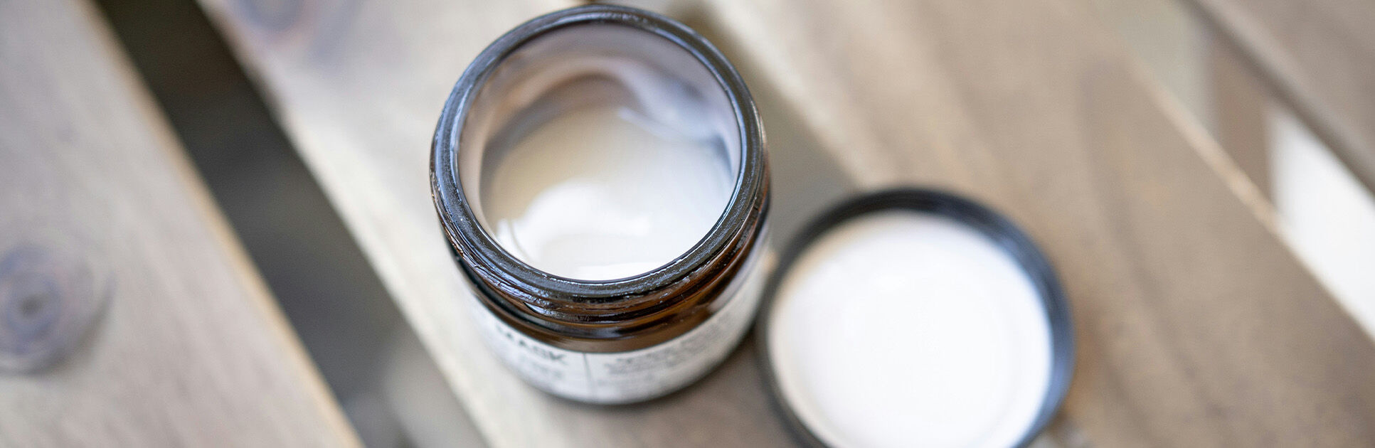 Pote de creme aberto em superfície de madeira