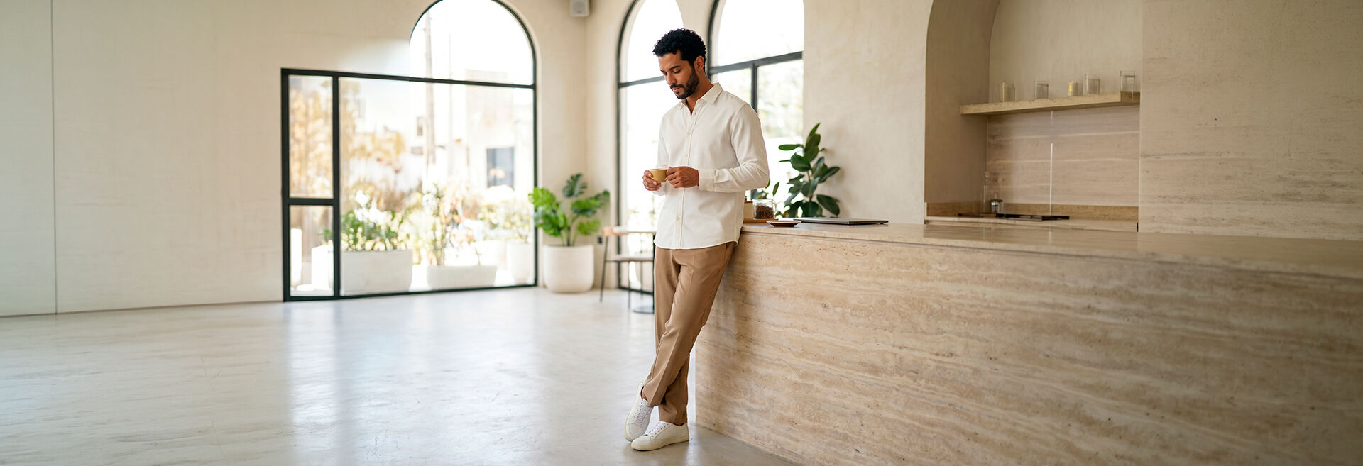 Homem segurando café em ambiente moderno e minimalista.