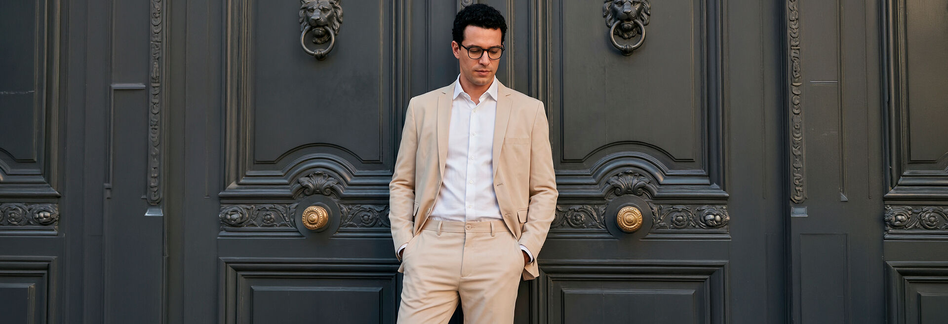 Homem elegante vestido com terno claro em frente a porta
