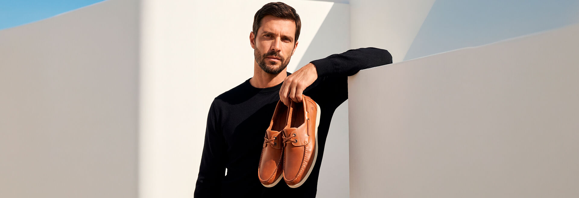 Homem segurando sapatos de couro em cenário moderno