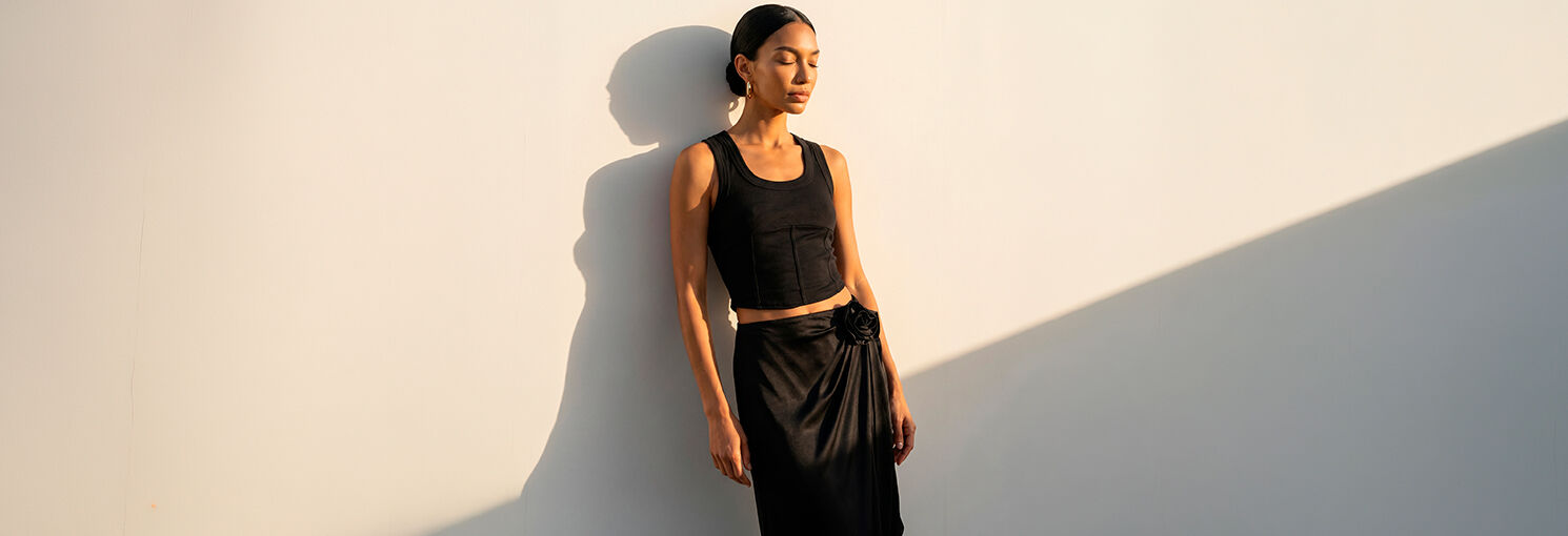 Modelo vestindo blusa preta e saia de couro