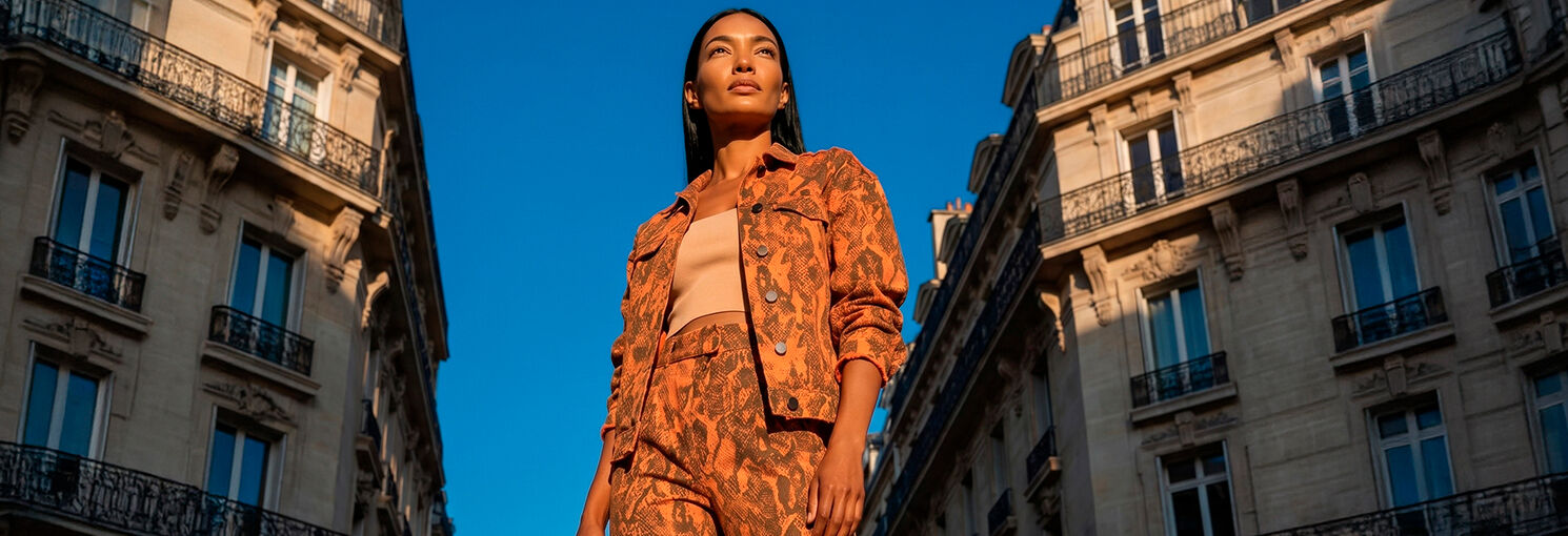 Modelo em traje laranja sob céu azul claro