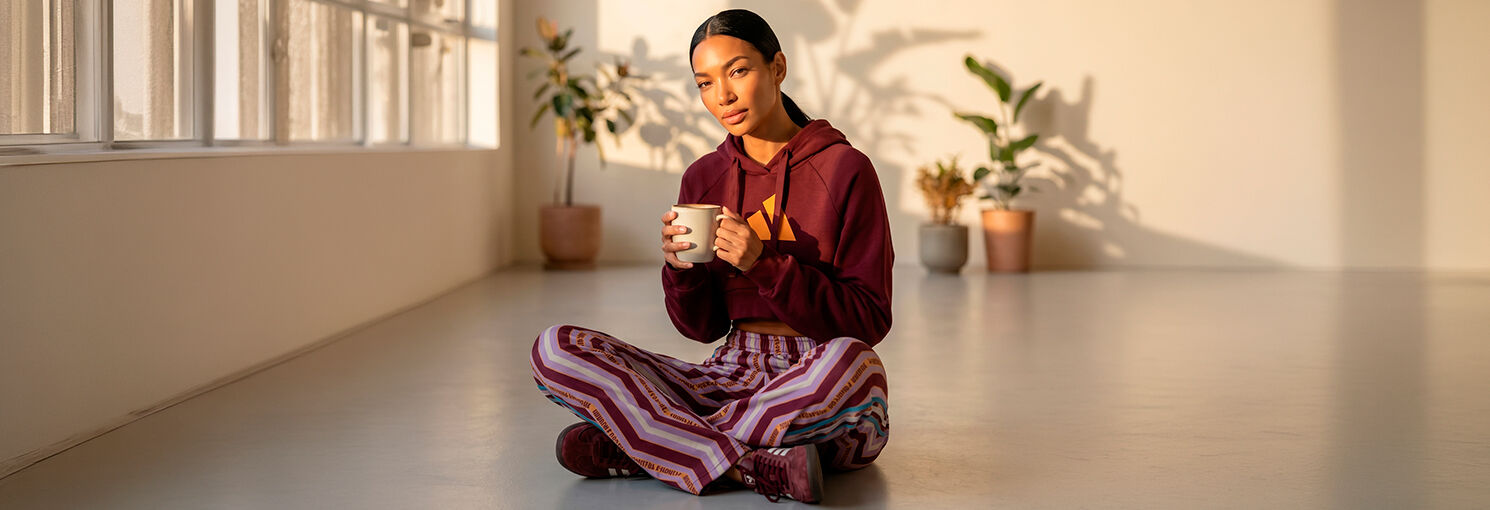 Mulher sentada com roupa confortável e caneca de café.
