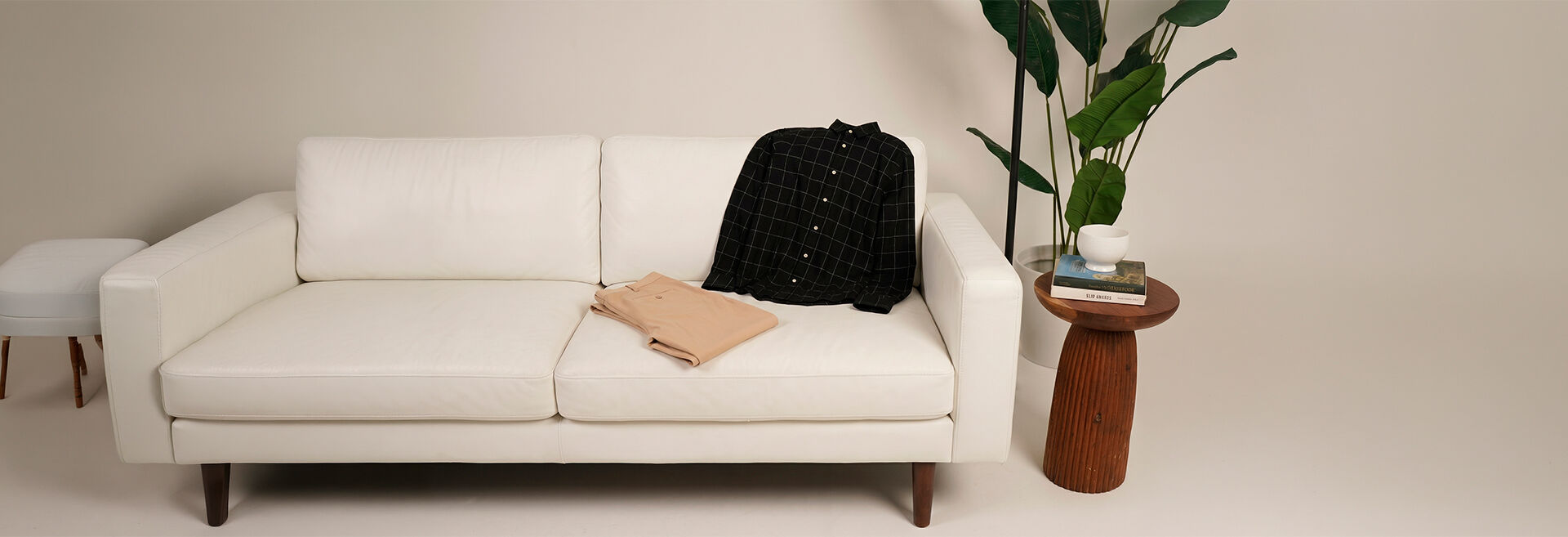 Sofá branco com camisa e plantas decorativas ao fundo