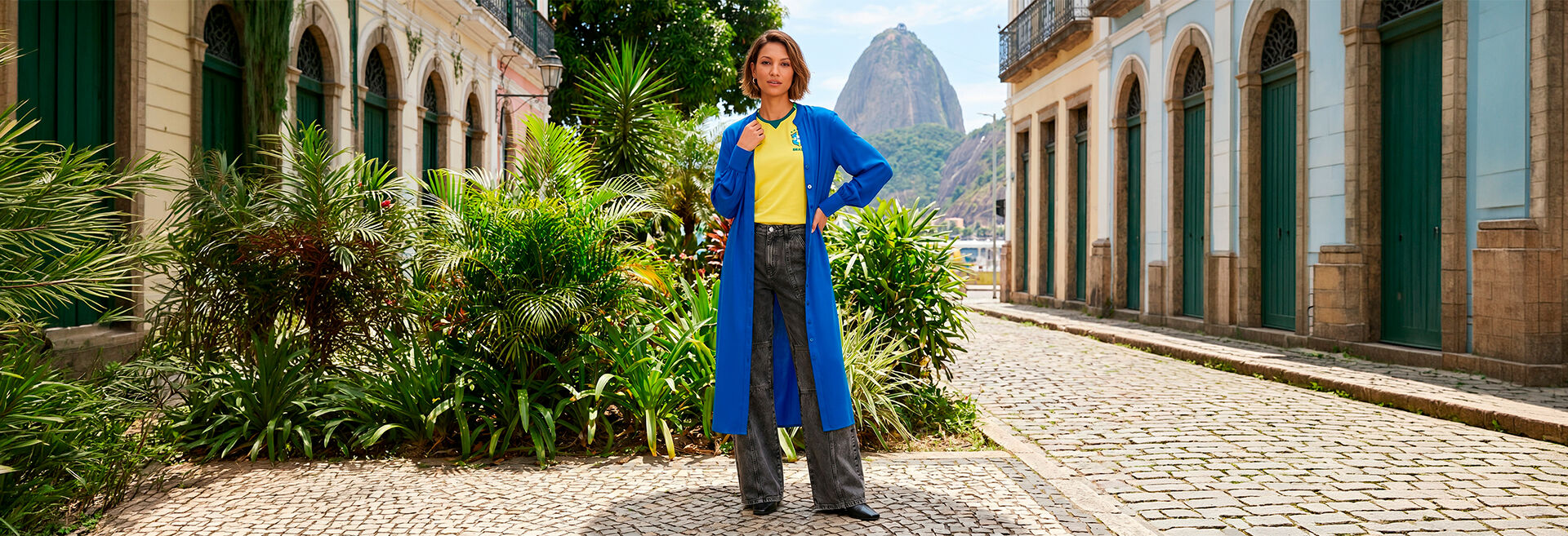 Mulher em roupa azul em calçadão com montanha ao fundo